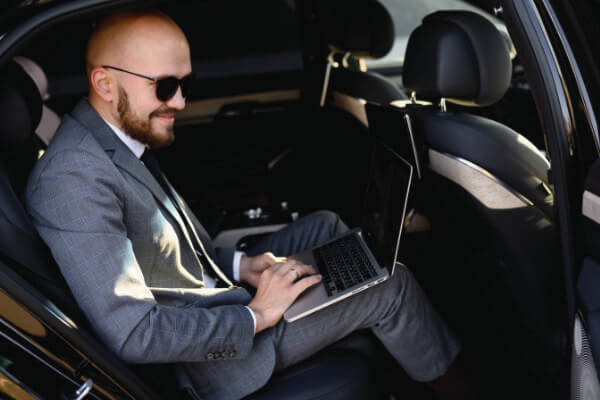 Photo of businessman in the back of a Black Car Service on his laptop. 