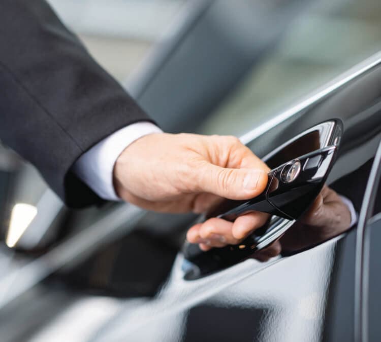 Photo of man's hand in a suit reaching to open the car door of a corporate black car service.